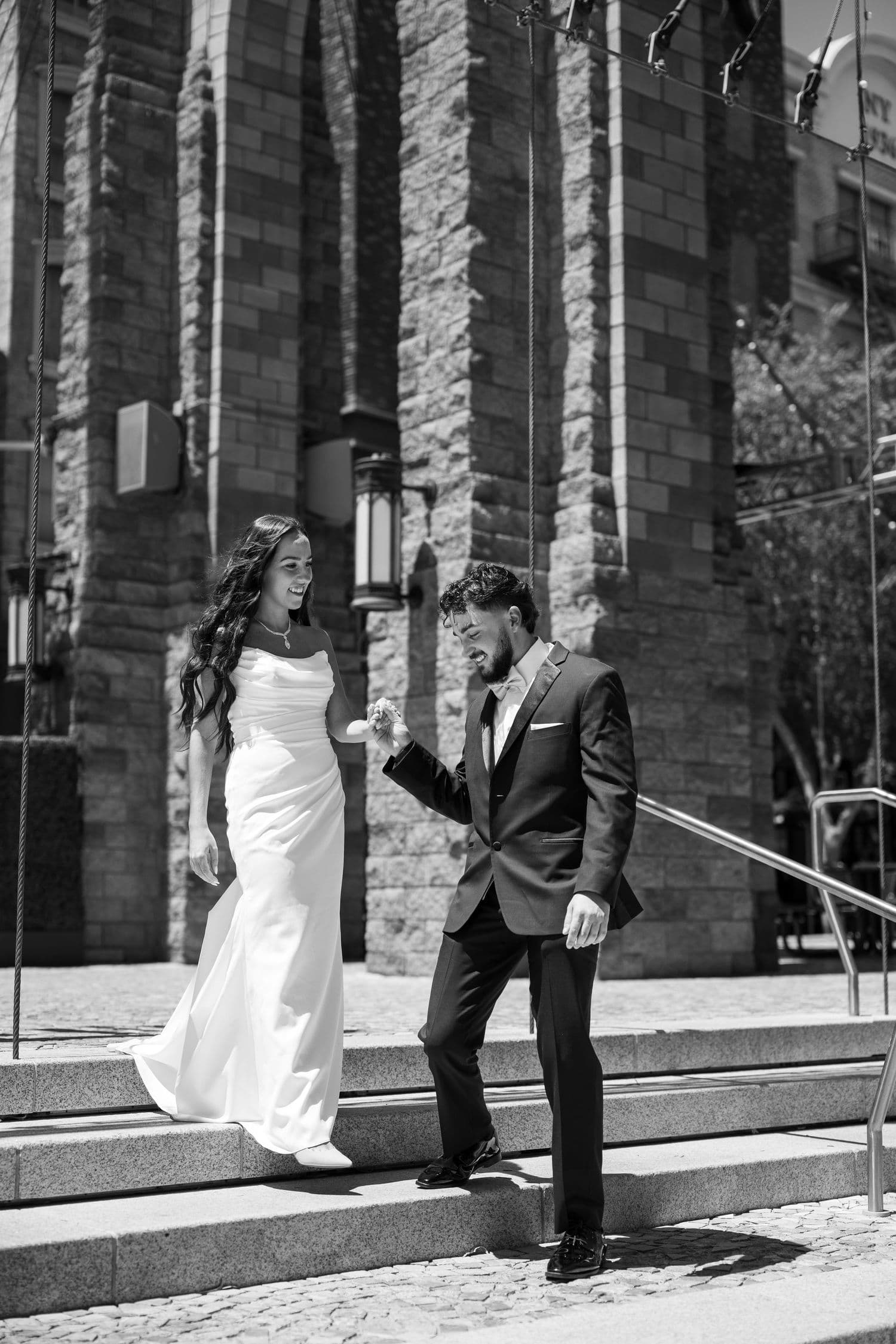 Black and white photo of newlyweds posing playfully on stone steps