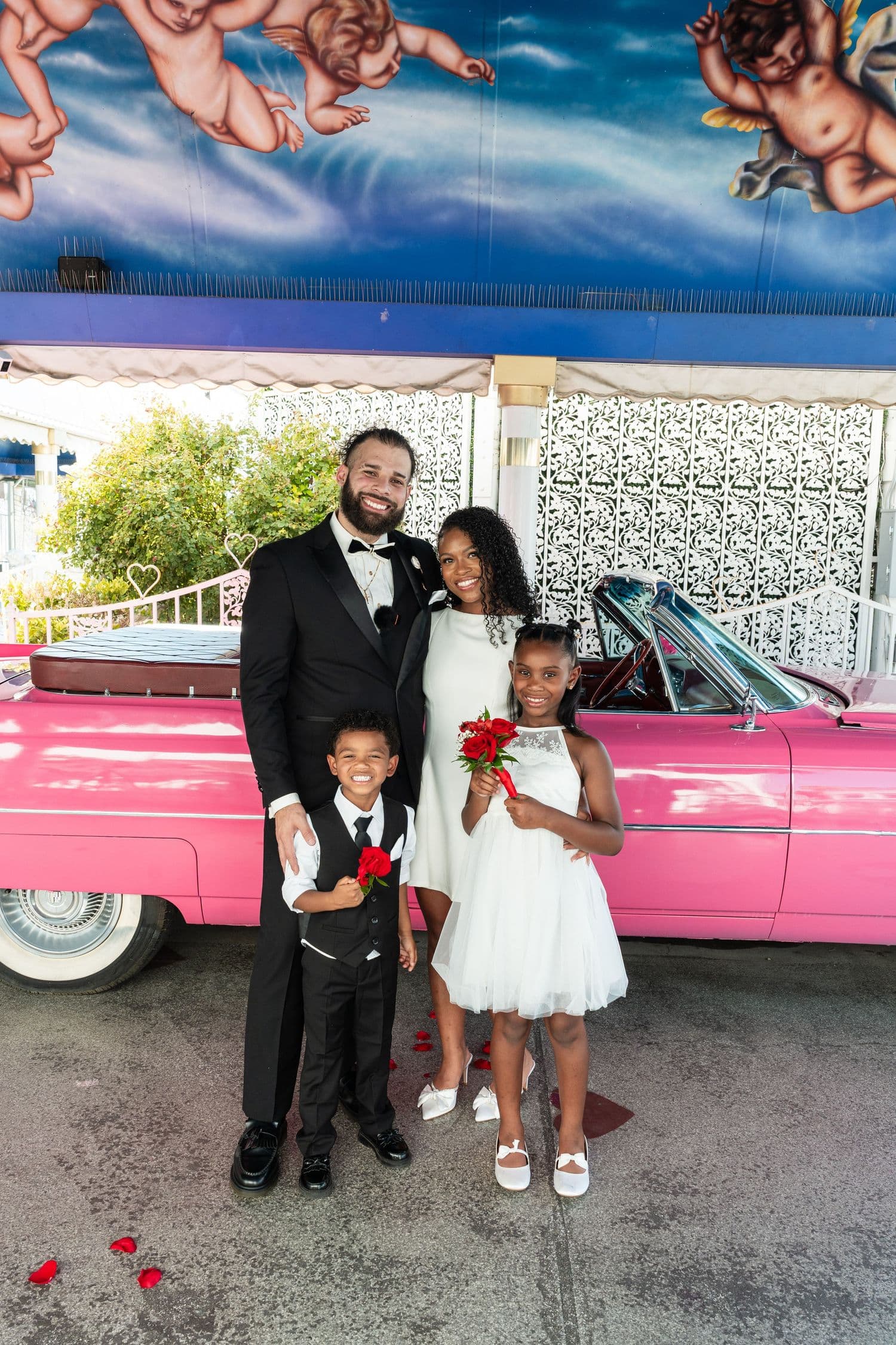 Wedding party by the pink car under a blue canopy