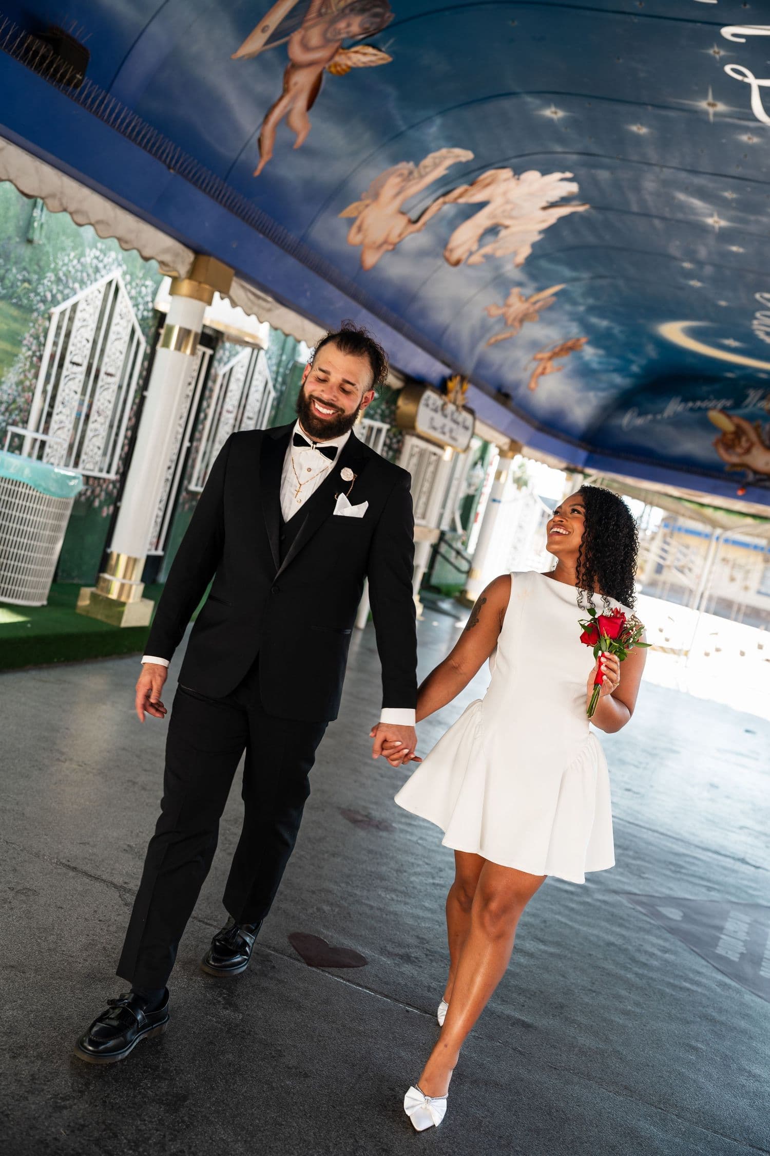 A couple walking beneath a decorated tunnel with painted cherubs