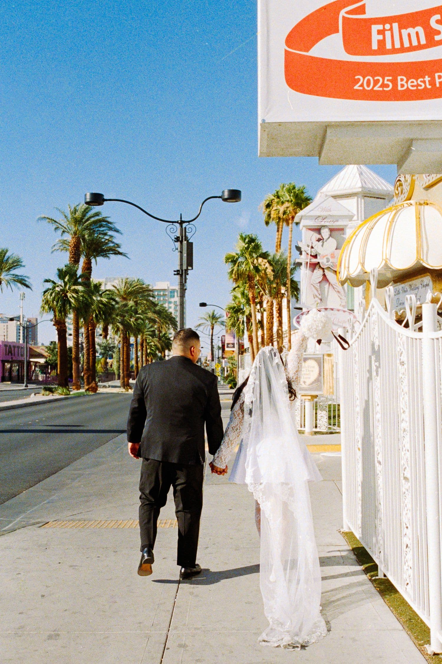 A couple walking down a palm-lined Las Vegas street