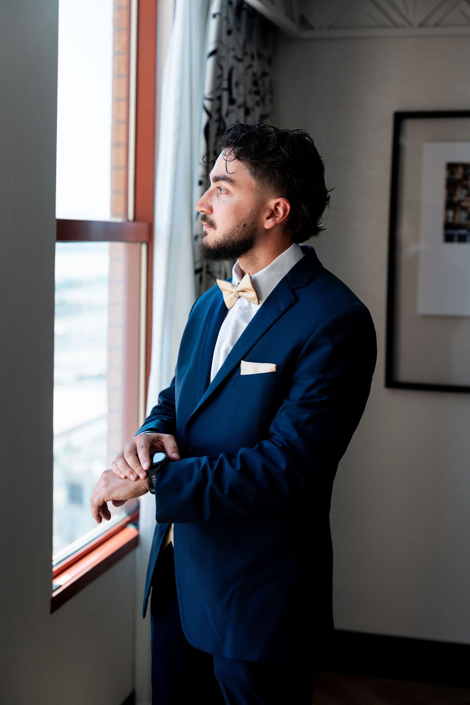 Person in a navy suit gazing out a bright window