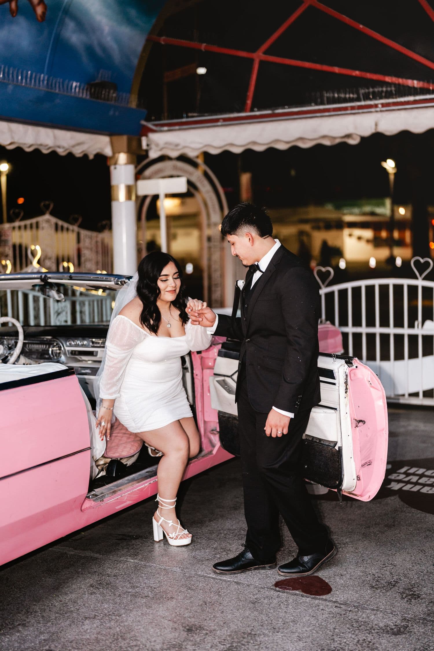 A couple beside a pink classic car
